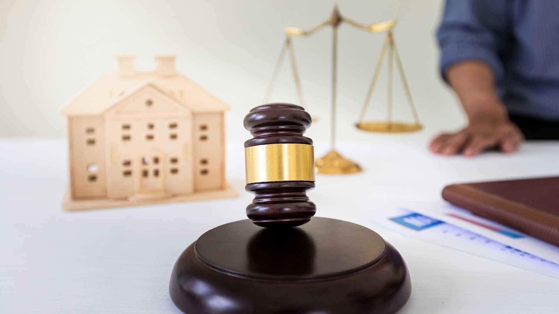 a gavel legal balance and wooden home figurine on a desk